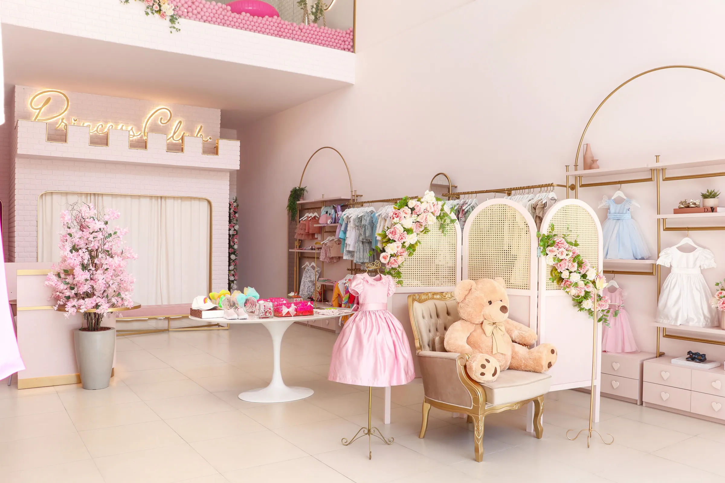 Interior da loja infantil Princess Club, com fachada de castelo, flores e vestidos de festa